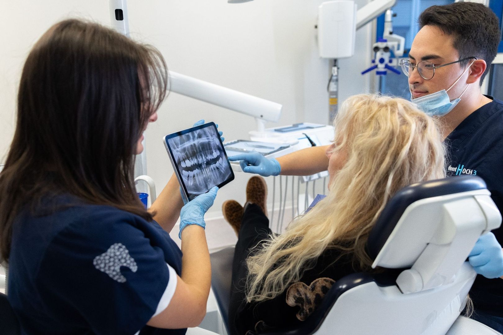 Zahnarzt und Assistentin besprechen mit einer Patientin das Röntgenbild