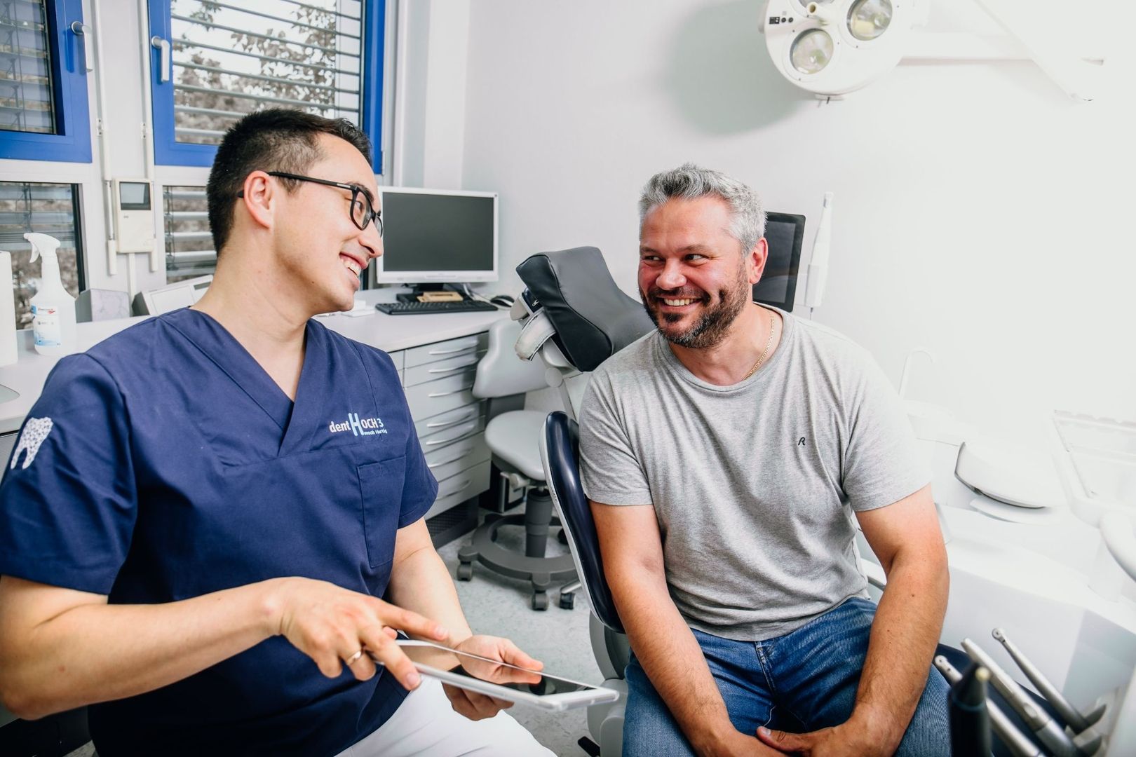 Zahnarzt im Gespräch mit einem lachenden Patienten